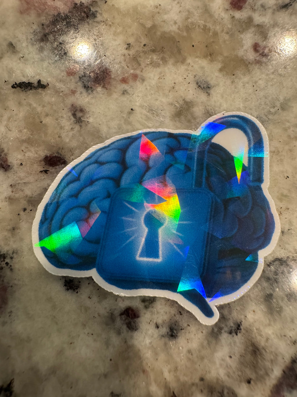 A die-cut holographic sticker featuring a blue brain and padlock.