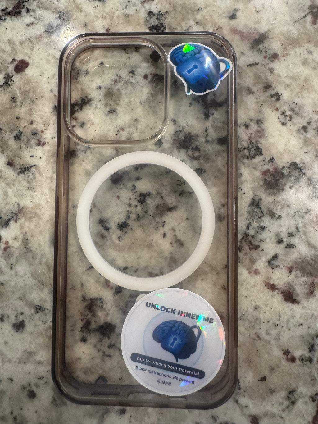 A round holographic NFC sticker on phone case for display only. The sticker features a blue brain and padlock graphic with the text 'UNLOCK INNER ME', 'Tap to Unlock Your Potential', and 'NFC' printed at the bottom.